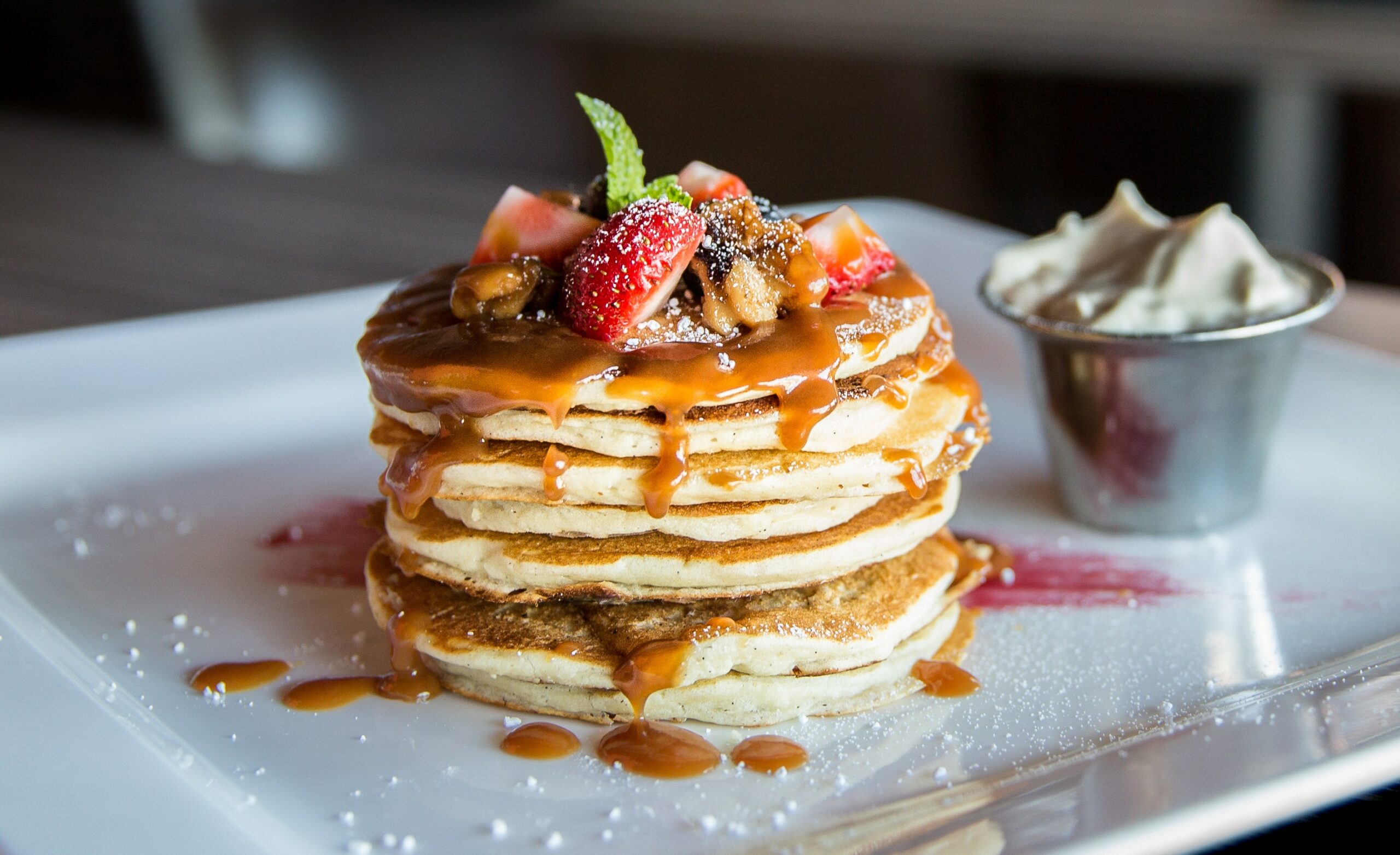 large stack of pancakes topped with fruit and syrup with butter on the side | breakfast West Roxbury