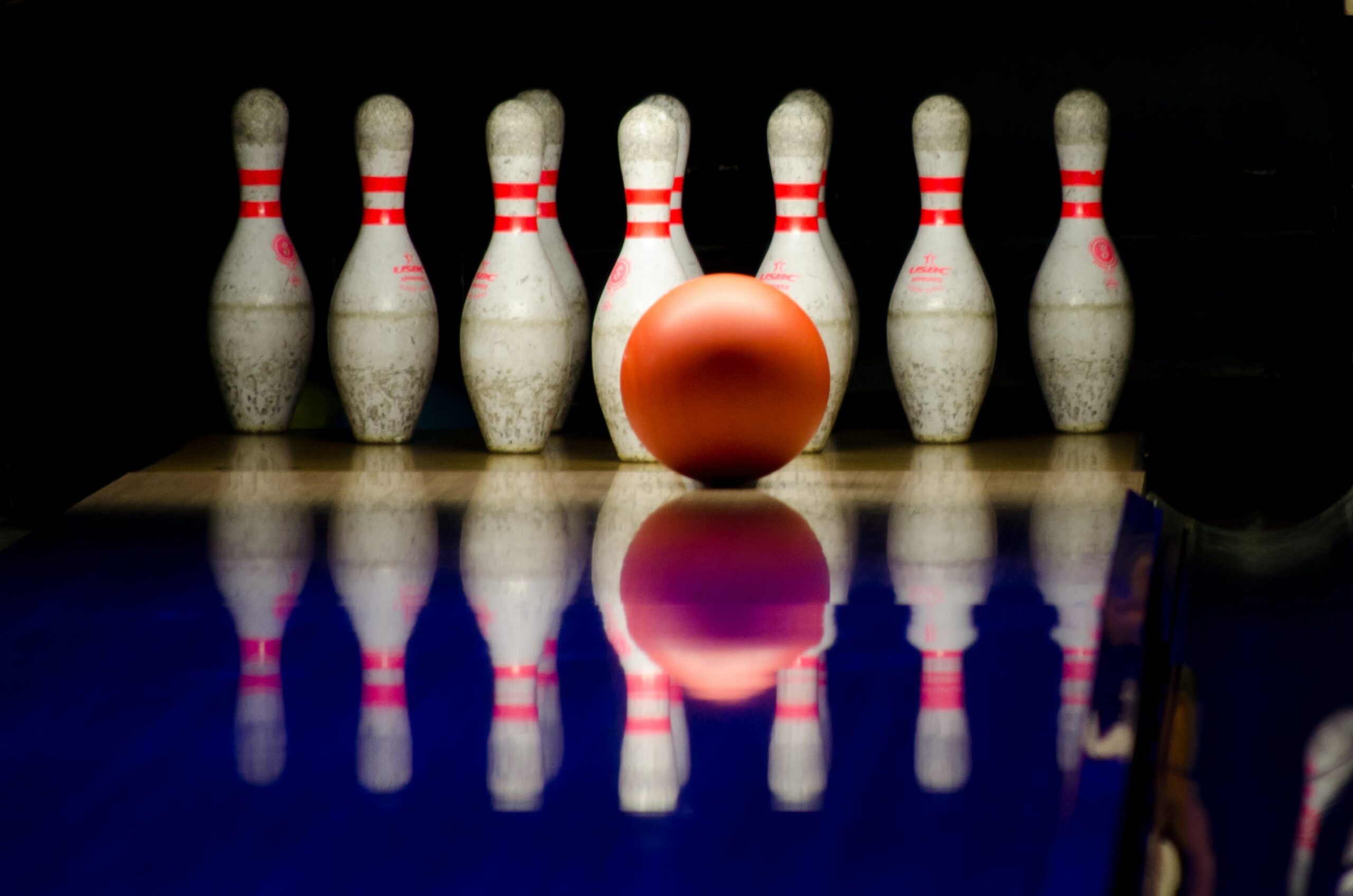 a red bowling ball in front of ten pins at a bowling alley | bowling West Roxbury
